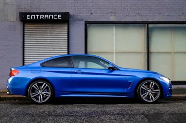 Niebieskie sportowe coupe BMW zaparkowane przy budynku z napisem ENTRANCE.