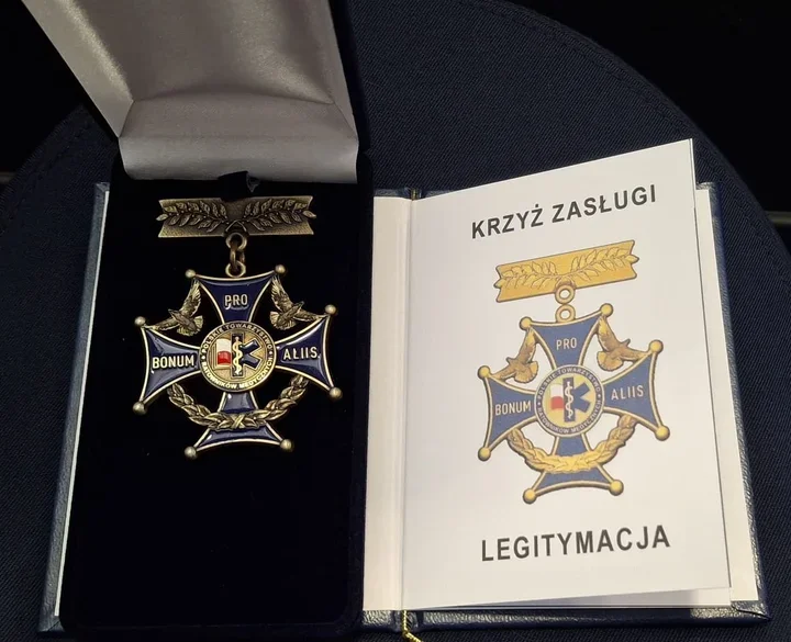 Otwarte etui z Krzyżem Zasługi Polskiego Towarzystwa Ratowniczego oraz legitymacją odznaczenia.