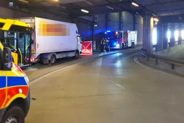 Pojazdy służb ratunkowych, autobus i ciężarówka w tunelu podczas nocnej interwencji.