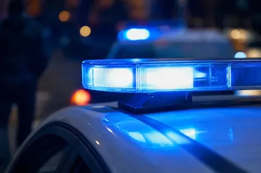 Migające niebieskie światła na dachach policyjnych radiowozów w nocy.